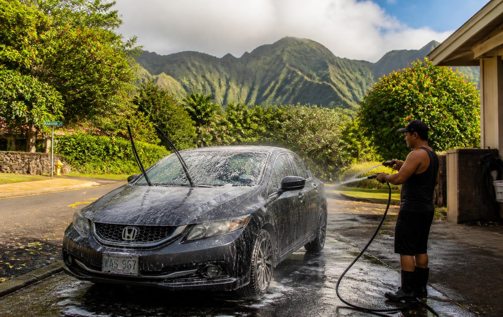 Car being hand-washed in a Kaneohe driveway with the Koolau mountains behind
